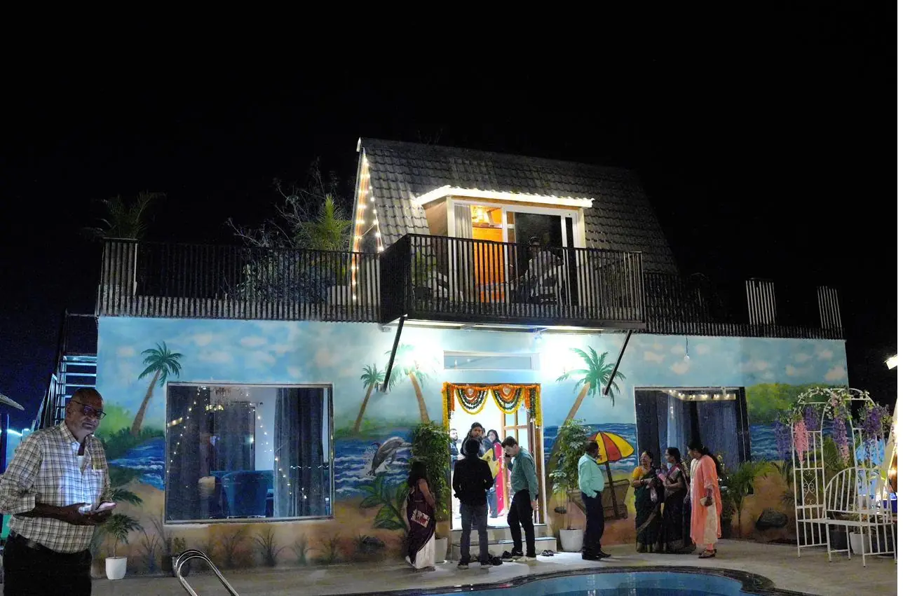 Guests gathered at the decorated common hall at night, marigold garlands over the door