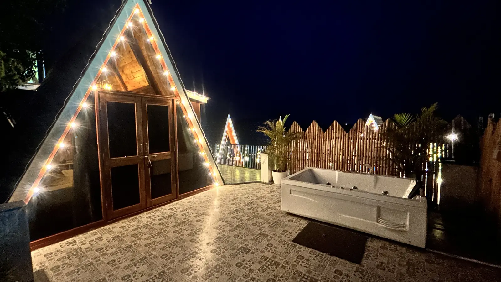 The Terrace Cottage at night, outlined with bulbs, beside an open-air jacuzzi