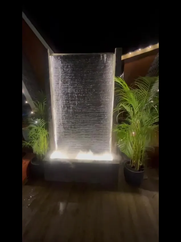 Illuminated water wall between palms at night